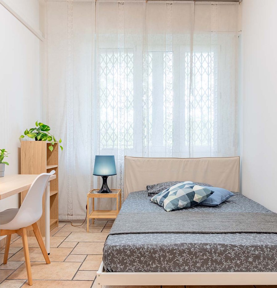 Stanza luminosa con letto, scrivania e finestra